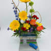 Colorful flower arrangement in a diner-shaped container with a blue toy car