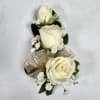 This wrist corsage features three white spray roses, babies breath and white