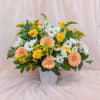 Mixed bouquet of peach gerbera daisies, yellow roses, and white daisies in a white vase