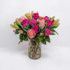 Pink and peach roses with lilies and carnations in a glass vase