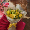 Yellow bouquet with lilies, roses, and calla lilies on a pink chair