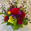 A glass bowl with rich, jewel toned flowers. Ruby, sapphire, emerald, citrine