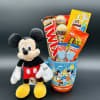 Mickey Mouse plush beside a Disney-themed cup filled with candy bars and lollipops