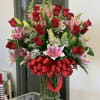 Bouquet of red roses and pink lilies in a glass vase with a red ribbon