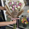 Bouquet of pink and white roses wrapped in brown paper with a pink ribbon