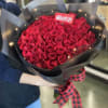 Large bouquet of red roses wrapped in black paper with a plaid ribbon