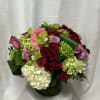 Mixed bouquet of red, pink, and white flowers in a glass vase