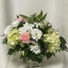 Pink and white flowers arranged in a clear glass vase