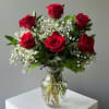 Red roses arranged in a clear glass vase with white baby's breath