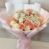 Bouquet of pink and cream roses with baby's breath in pink wrapping
