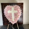 Heart-shaped pink rose wreath with a white floral cross on an easel