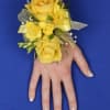 Yellow rose wrist corsage with ribbon on a person's hand
