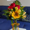 Bouquet of red roses and yellow flowers in a glass vase with a ribbon