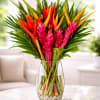 Tropical bouquet of pink and orange flowers in a clear glass vase