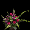 Hot pink roses and purple orchids rise from a tall glass vase