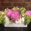 Pink peonies and green orchids in a white rectangular vase