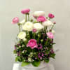 Pink and white ranunculus arrangement in a white ceramic bowl with small purple accent flowers