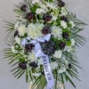 Standing funeral wreath of white flowers and dark roses with a ribbon