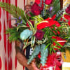 Large bouquet of red roses and tropical foliage held by a man