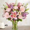 Pink roses and lilies arranged with gerberas in a clear glass vase
