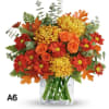 Autumn bouquet of red, orange, and yellow flowers in a clear glass vase