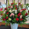 Large mixed flower arrangement in a white vase with red, pink, and white blooms