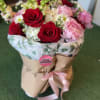 Bouquet of red and pink roses with white blooms in brown paper wrap