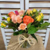 Bouquet of orange, peach, and yellow roses in a glass vase