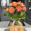 Bouquet of orange roses in a glass vase with a burlap ribbon