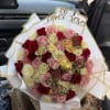 A lush, rounded spray of roses in blush pink, deep red, creamy