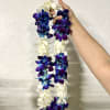 Two purple and white orchid leis held by a hand