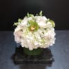 White floral arrangement in a glass vase with green accents