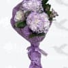 Lavender hydrangea bouquet wrapped in purple paper with a ribbon