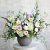Large pastel arrangement of roses, hydrangeas and mixed blooms in a gray bowl vase on a pedestal table