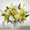 Yellow and white chrysanthemums, daisies, and hydrangeas arranged in a white vase.