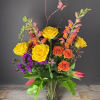 Tall mixed bouquet of yellow and orange roses with snapdragons, purple blooms and tulips in a clear glass vase