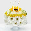 White daisies and yellow flowers arranged like a cake with lit candles