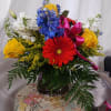 Bright mix of flowers in a vase.  Gerbera daisies, blue Delphinium