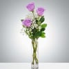 Lavender roses rise above a slim clear glass vase in a simple
