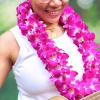 Woman wearing a bright pink orchid lei and holding a guitar