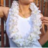 White orchid lei worn over a white tank top