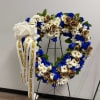Heart-shaped floral wreath with blue, white, and gold flowers on a stand