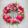 Pink and red rose wreath on a black stand