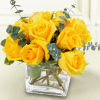 The bouquet is meticulously arranged inside a modern square glass cube vase