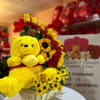 Yellow teddy bear in a wicker basket with red and yellow flowers
