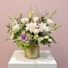 Mixed white and pale pink flowers arranged in a gold cylindrical vase