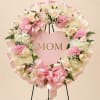 A heart-shaped floral wreath centered with a pink heart sign that reads