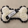 A tightly packed dog-bone tribute formed entirely of white chrysanthemums-designed to honor