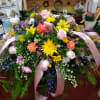 Large floral arrangement with pink roses, yellow daisies, and pink ribbons