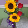 Two large yellow sunflowers and three deep red roses create a bold